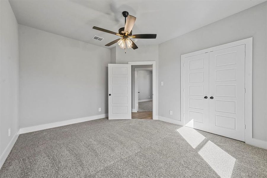 Unfurnished bedroom with carpet floors, a closet, baseboards, and a ceiling fan Unfurnished bedroom with carpet floors, a closet, baseboards, and a ceiling fan