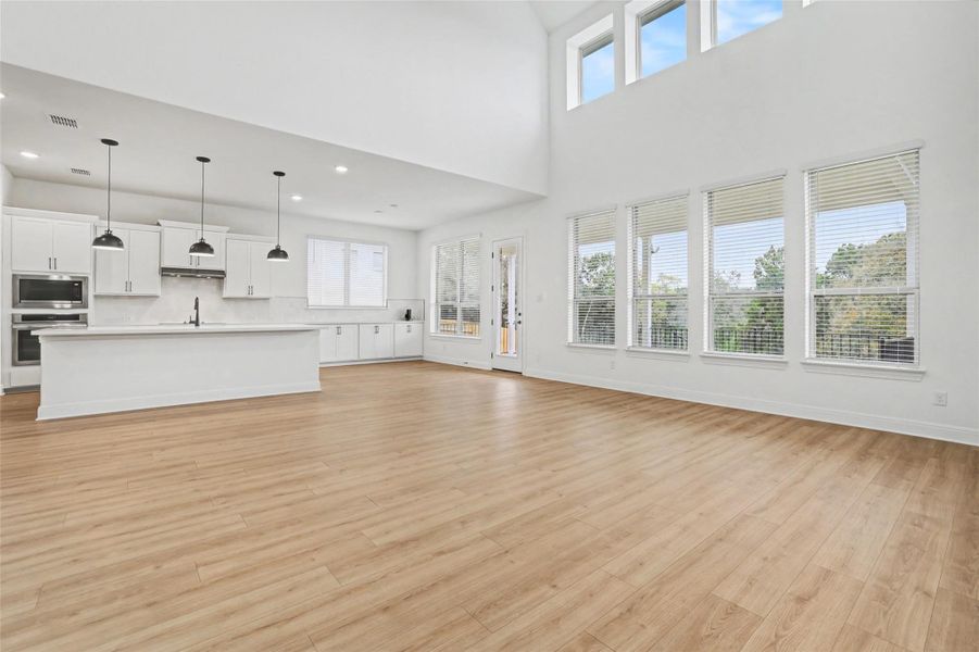 Unfurnished living room featuring light wood-style floors and a high ceiling