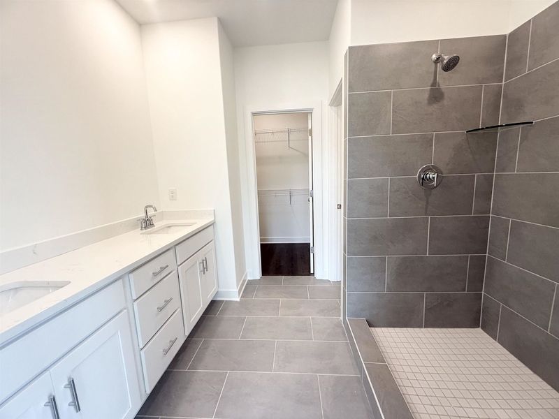 Spacious bathroom featuring a dual vanity with white cabinetry and a light-toned countertop