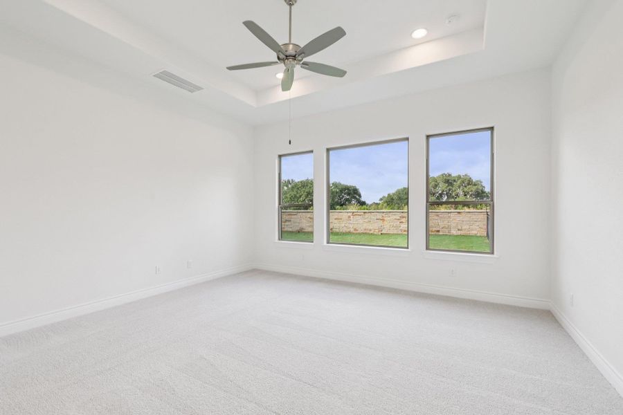 Empty room featuring a tray ceiling, light carpet, a ceiling fan, and recessed lighting