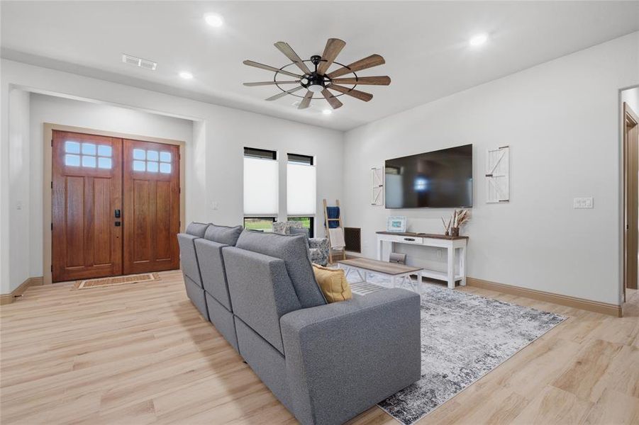 Spacious living area featuring light wood-finish flooring, recessed lighting, and a contemporary ceiling fan