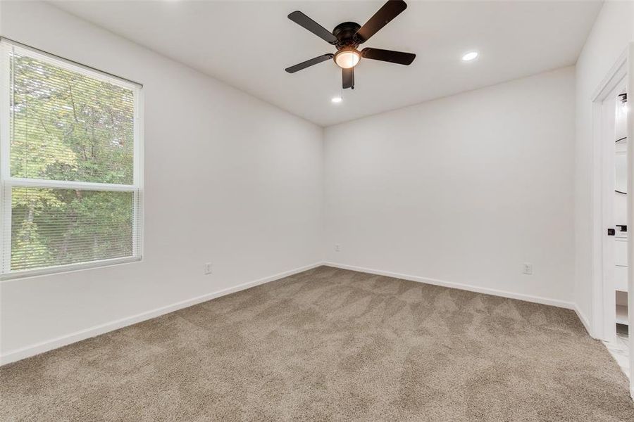 Carpeted spare room with a healthy amount of sunlight and ceiling fan