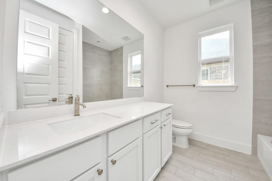 Secondary bath features tile flooring, walk-in shower with tile surround, light stained wood cabinets, beautiful light countertop. Secondary bath features tile flooring, walk-in shower with tile surround, light stained wood cabinets, beautiful light countertop.