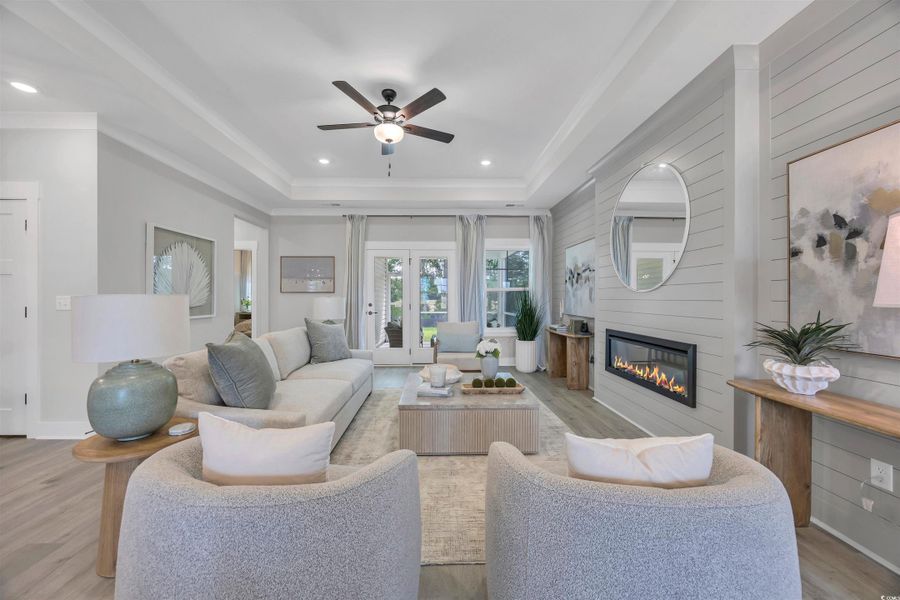 Living area featuring light wood-style flooring, a fireplace, recessed lighting, a tray ceiling, and ceiling fan