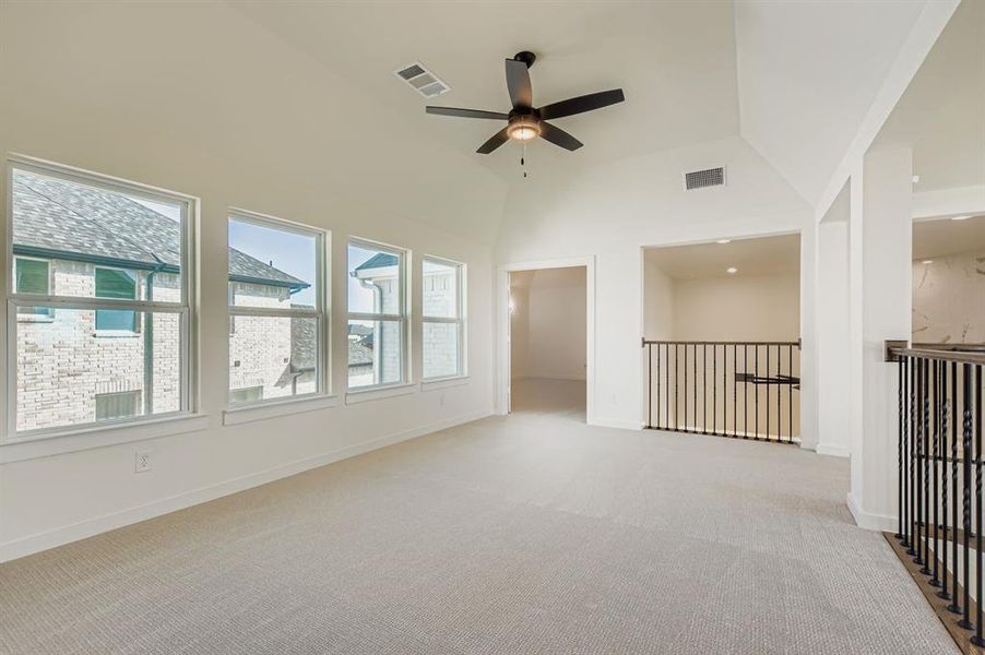 Spare room with light colored carpet, a ceiling fan, and high vaulted ceiling