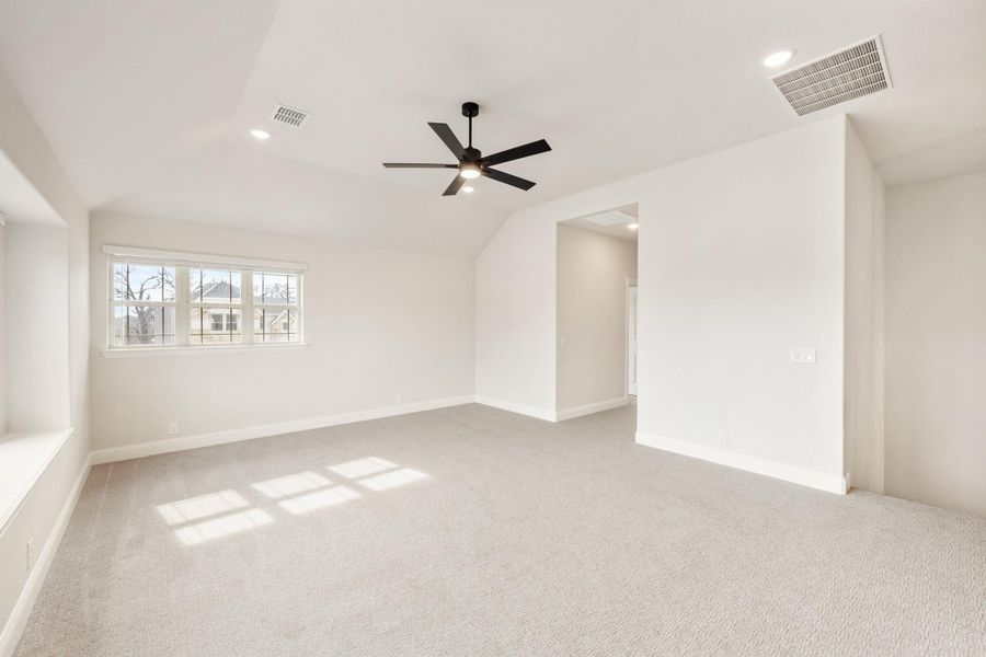 Empty bedroom with vaulted ceiling, black ceiling fan, carpet flooring, and a large window