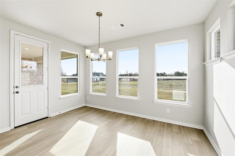Unfurnished dining area with a chandelier and light wood-style flooring