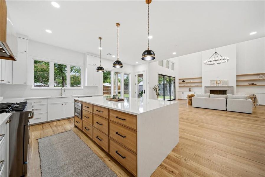 Kitchen with gas range oven, white cabinets, stainless steel microwave, and a center island