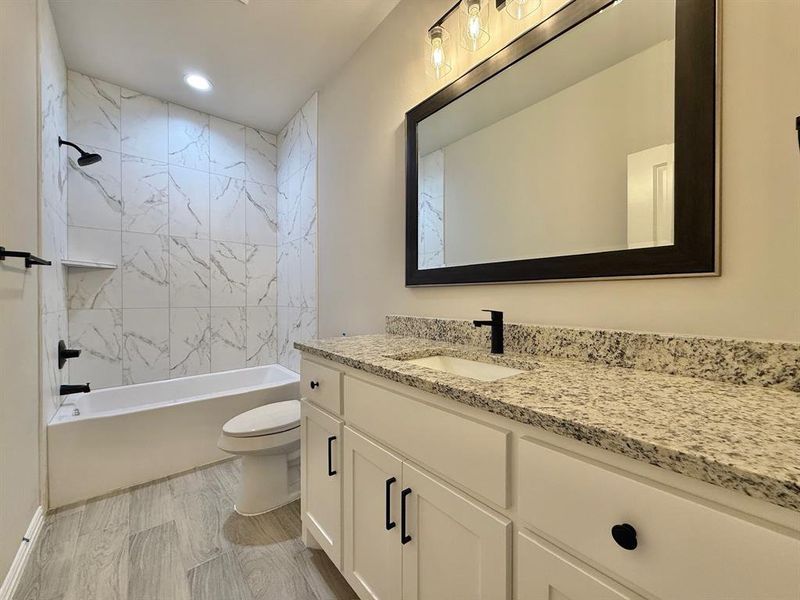 Full bathroom featuring toilet, tiled shower / bath combo, and vanity