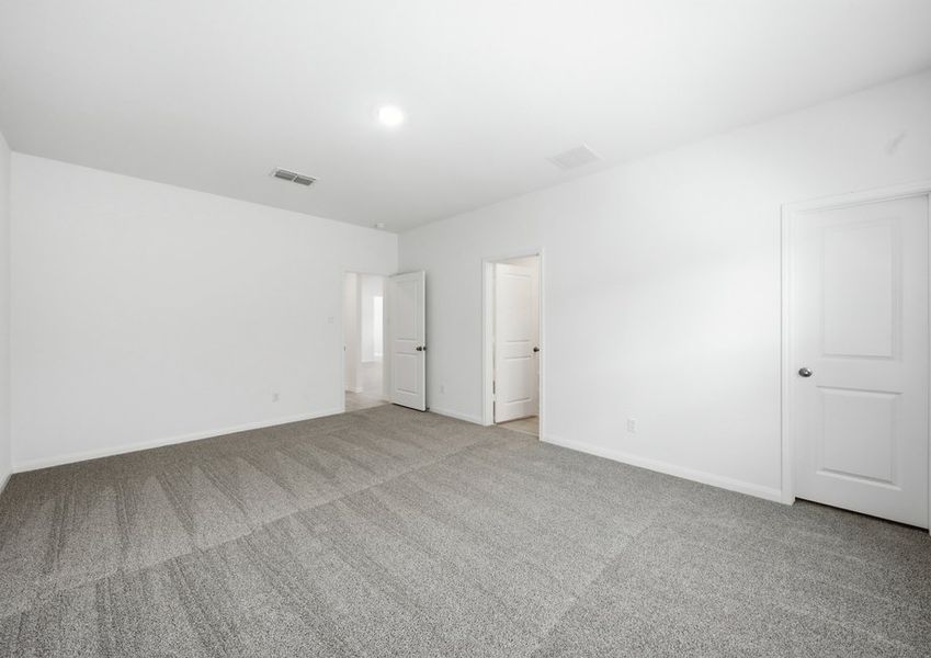 Primary bedroom featuring carpet flooring and a doorway to the ensuite master bath. Primary bedroom featuring carpet flooring and a doorway to the ensuite master bath.