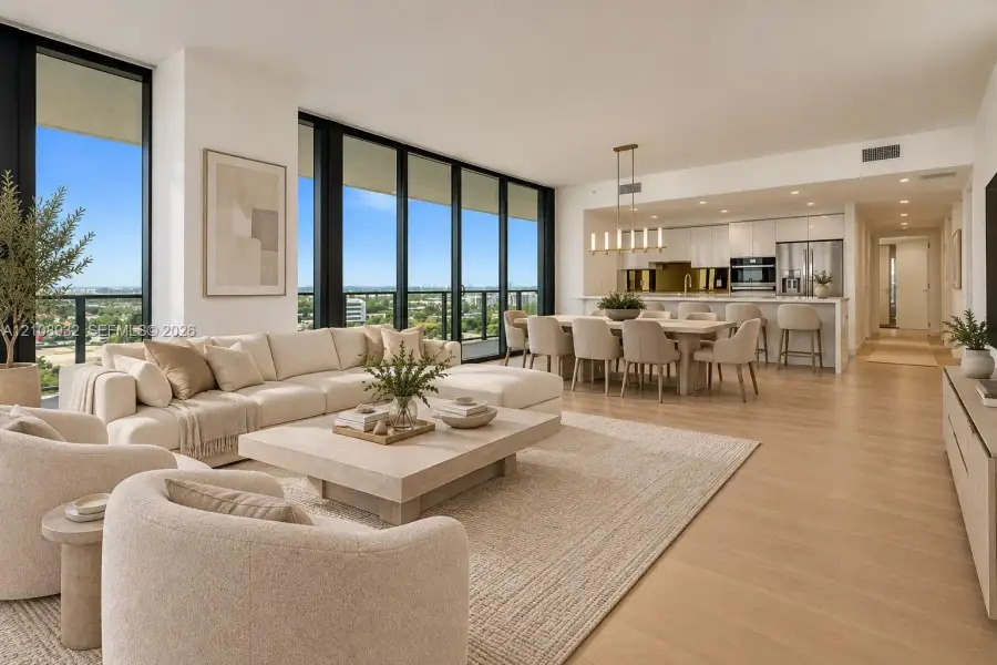Open-concept living space featuring floor-to-ceiling windows, wood-finish flooring, recessed lighting, and a modern kitchen with built-in stainless steel appliances