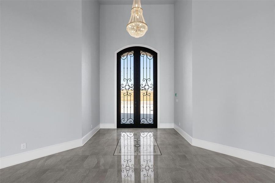 Entrance foyer featuring french doors, arched walkways, a towering ceiling, and a chandelier Entrance foyer featuring french doors, arched walkways, a towering ceiling, and a chandelier