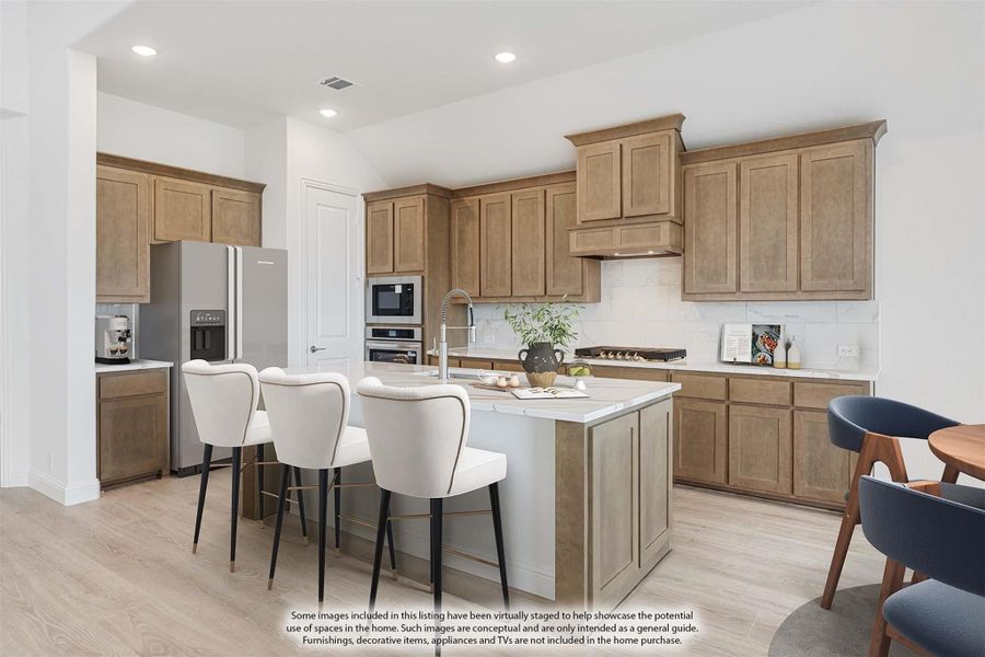 Kitchen with tan wood cabinets, center island with seating, stainless steel appliances, and light hardwood floors Kitchen with tan wood cabinets, center island with seating, stainless steel appliances, and light hardwood floors