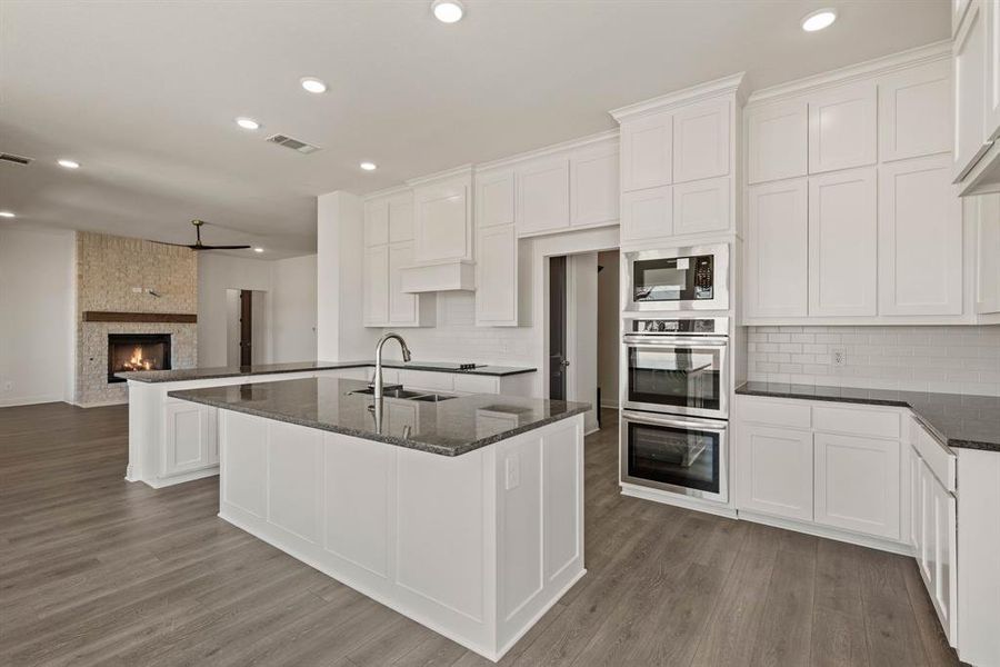 Kitchen featuring visible vents, a large fireplace, a sink, wood finished floors, and built in microwave