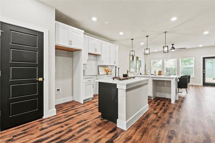 Kitchen featuring white cabinetry, a peninsula, recessed lighting, dark wood finished floors, and hanging light fixtures Kitchen featuring white cabinetry, a peninsula, recessed lighting, dark wood finished floors, and hanging light fixtures