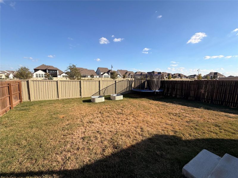 Fenced backyard featuring a residential view and a trampoline Fenced backyard featuring a residential view and a trampoline