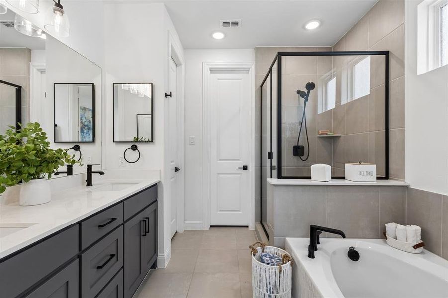 The spa-inspired bath features dual vanities, oversized mirrors, and contemporary finishes that blend style with everyday functionality.