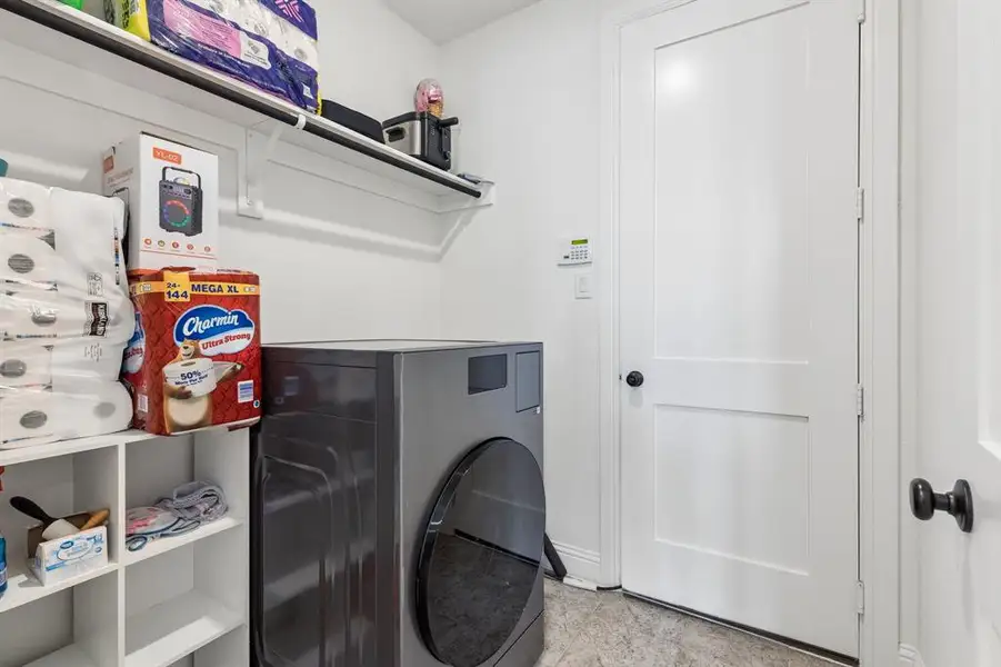 Dedicated utility area featuring white panel doors, built-in shelving, and a dark front-loading appliance