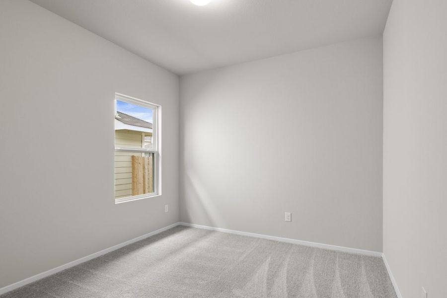 Image of a bedroom with cream walls, tan carpeting, a window, and white trim