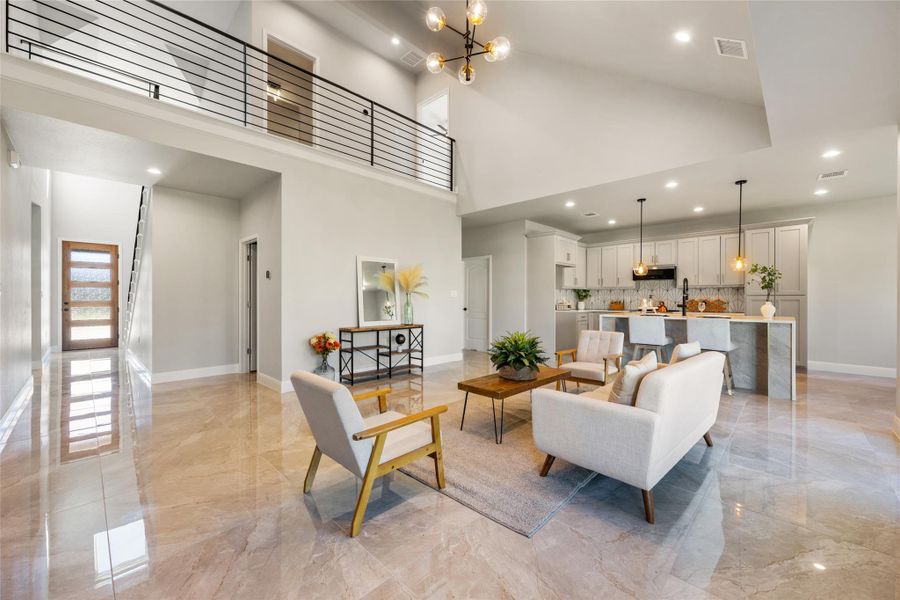 Living area with a chandelier, high vaulted ceiling, light marble finish floors, and recessed lighting