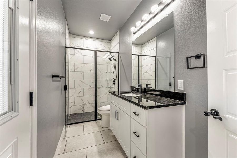 Bathroom with toilet, tile patterned flooring, vanity, and walk in shower