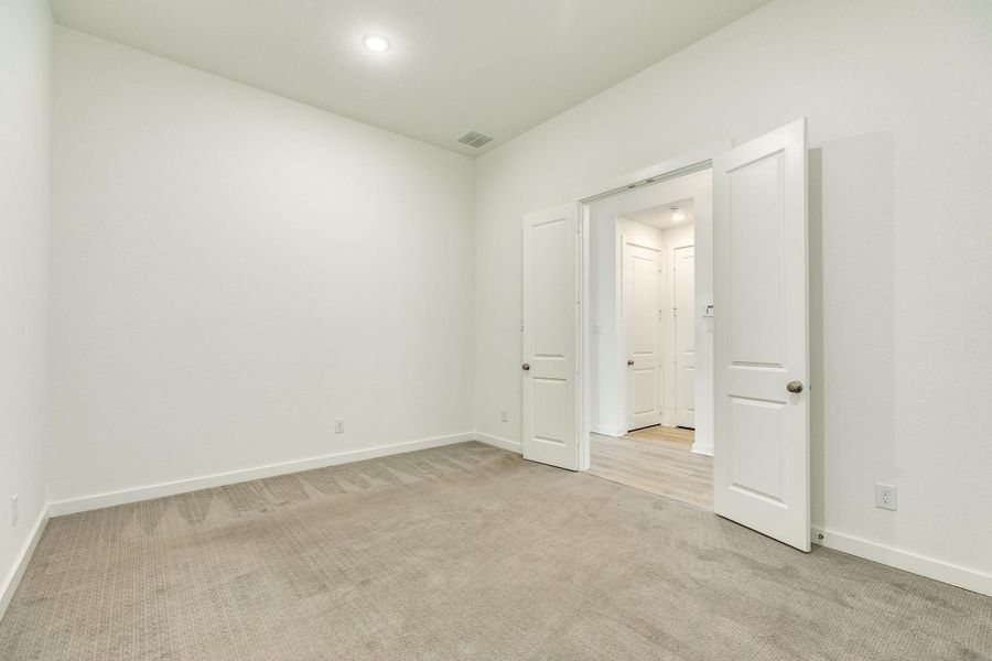 Spacious media room featuring plush, like-new carpeting, elegant double-door entry, and modern recessed lighting.