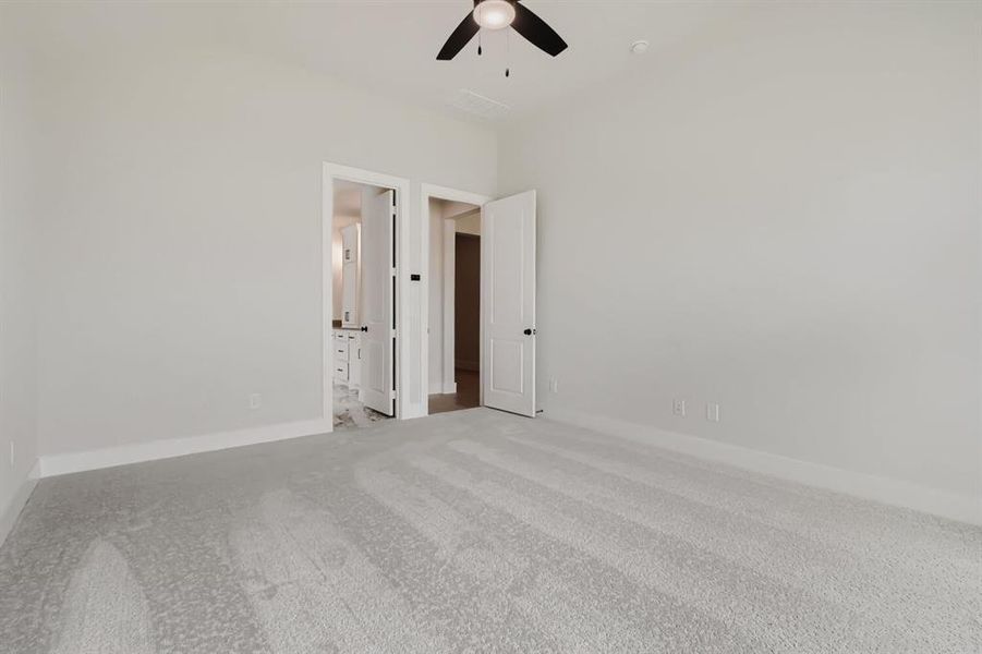 Spacious main bedroom room featuring vaulted ceilings, a contemporary ceiling fan, and light-toned carpet flooring