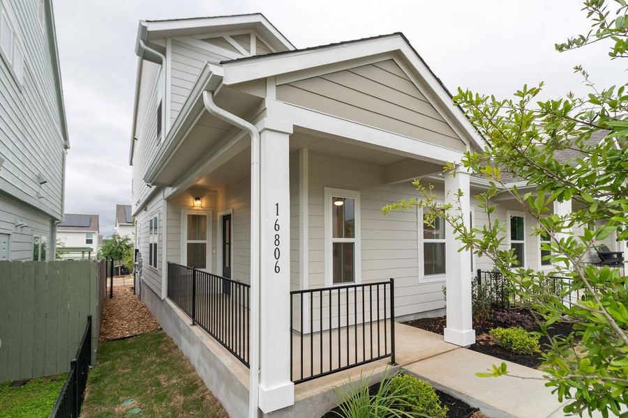 The property features a welcoming covered porch with a black metal railing and a concrete walkway