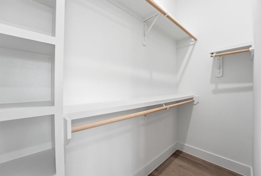 Spacious walk-in closet featuring custom built-in shelving, double hanging rods, and a clean, organized layout designed to maximize storage and functionality.