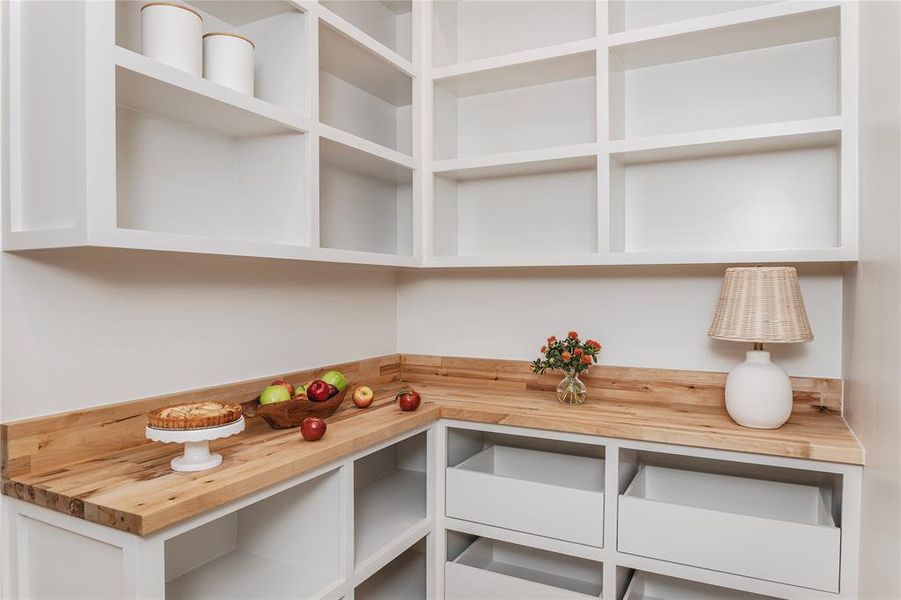 Walk-in pantry with a butcher block counter and custom built shelving and drawers! On the other wall is space for a second refrigerator.