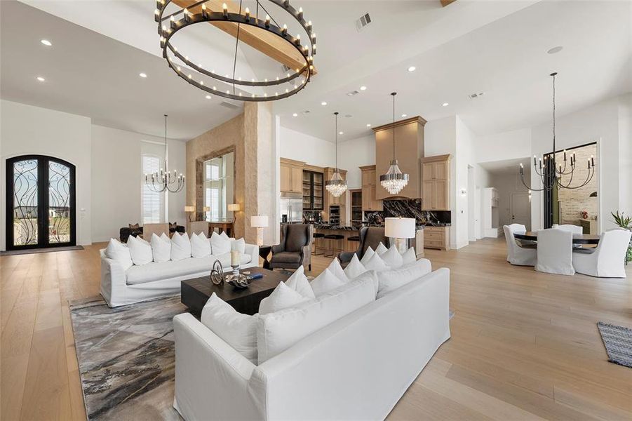 Living area featuring a chandelier, recessed lighting, light wood-style floors, and a towering ceiling