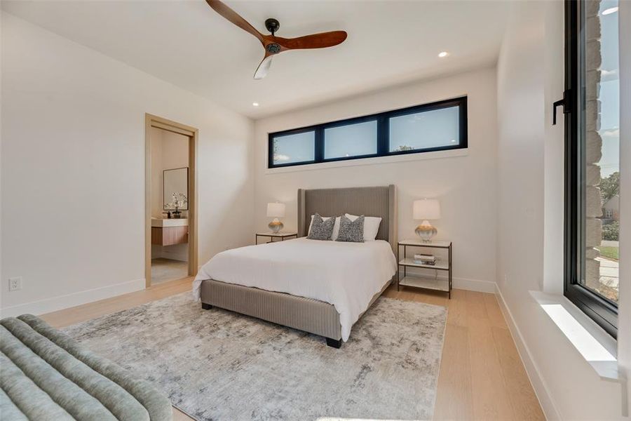 Bedroom with connected bathroom, ceiling fan, and light hardwood / wood-style floors