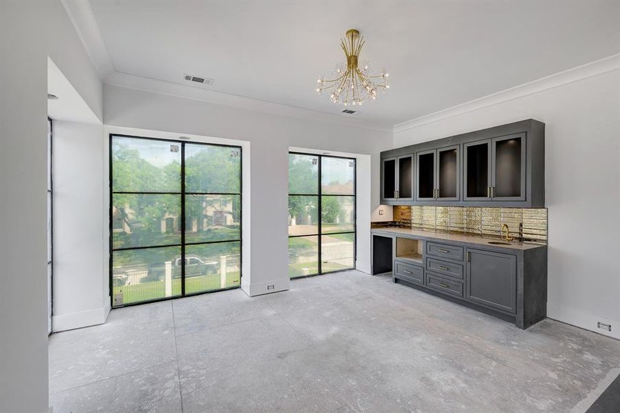 The primary suite also includes a retreat area with built-in cabinets, sink, plus space for a mini fridge and microwave. Large windows overlook the front yard. Stage of construction as of April 17, 2025. The primary suite also includes a retreat area with built-in cabinets, sink, plus space for a mini fridge and microwave. Large windows overlook the front yard. Stage of construction as of April 17, 2025.