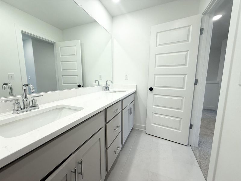 Full bathroom with double vanity and baseboards