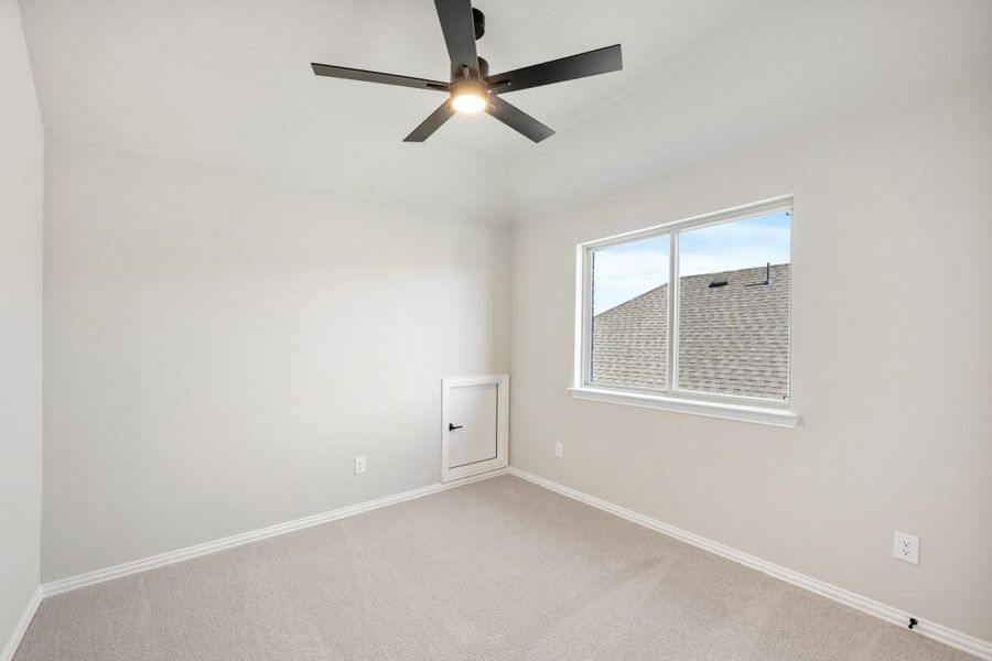 Empty bedroom with carpet flooring, black ceiling fan, single window, and small access panel on wall Empty bedroom with carpet flooring, black ceiling fan, single window, and small access panel on wall