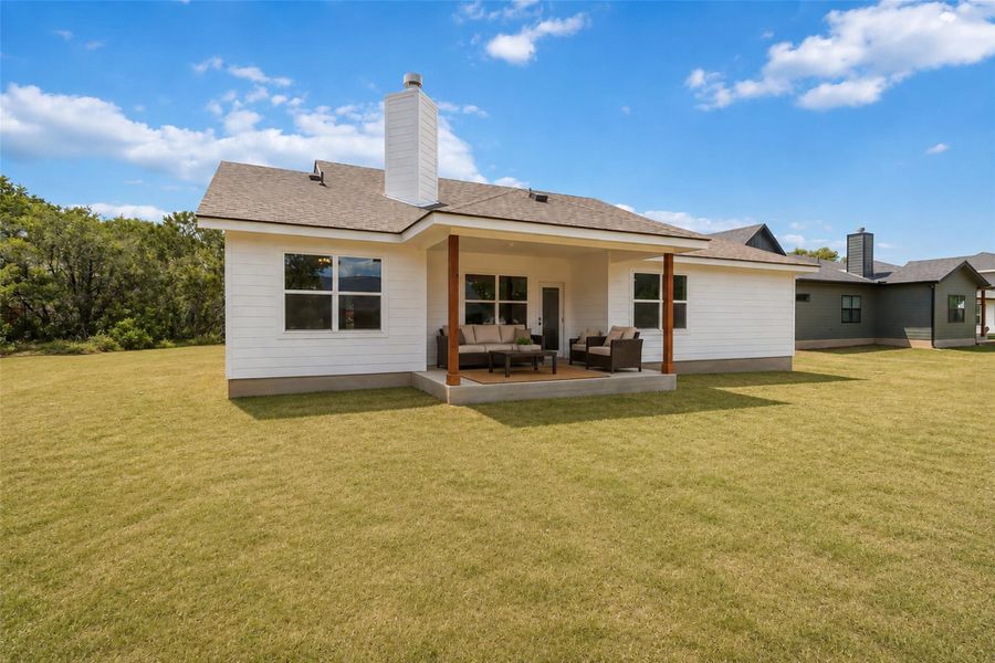Back of home with virtually staged patio and green color added to the grass