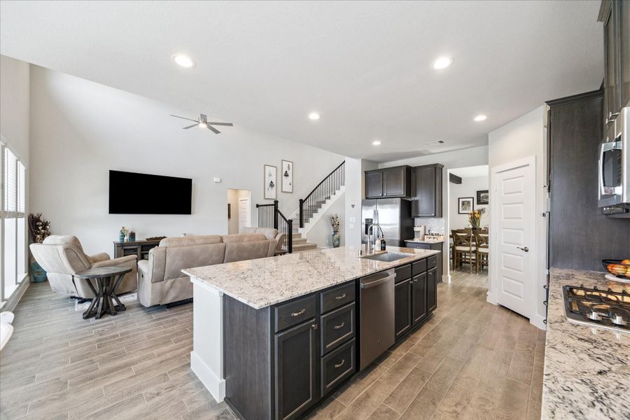 Modern open-concept kitchen and living area with granite island, stainless steel appliances, and tile flooring. Modern open-concept kitchen and living area with granite island, stainless steel appliances, and tile flooring.