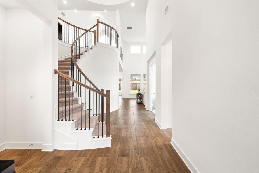 A grand spiral staircase commands attention in this inviting, naturally illuminated foyer.