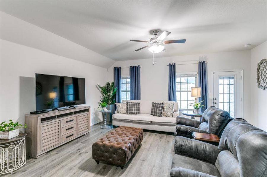 Living room with ceiling fan, vaulted ceiling, and light wood-type flooring