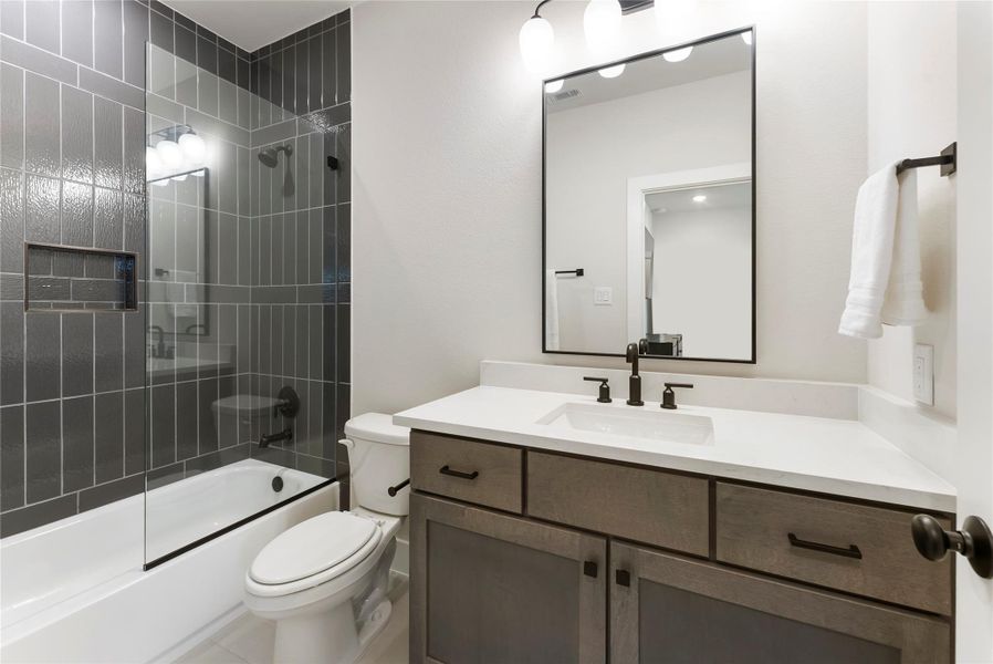 En-suite bath includes a walk in shower with upgraded tile to the ceiling, black hardware, and a clean vanity design. Full bath access for each bedroom adds privacy and convenience for family or guests.