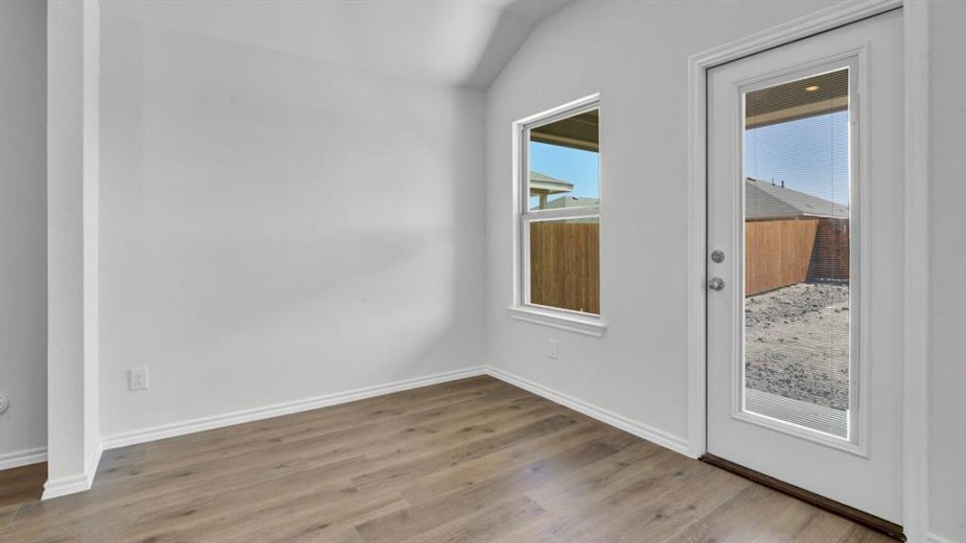 Unfurnished room with wood finished floors and lofted ceiling