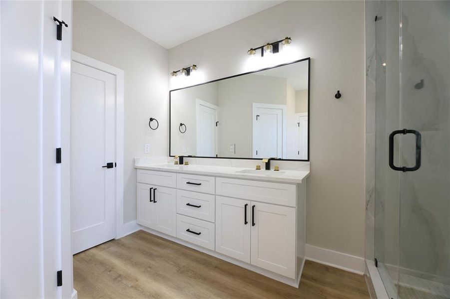 Primary Bathroom features dual vanities, glass encased walk-in shower and separate soaking tub.