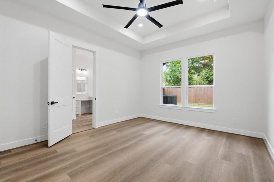 In the primary suite, large windows frame views of the private backyard, while an open doorway leads directly into the spa-like primary en-suite. In the primary suite, large windows frame views of the private backyard, while an open doorway leads directly into the spa-like primary en-suite.