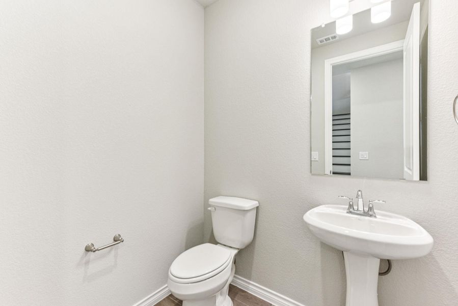 Half bathroom featuring a textured wall and wood finished floors Half bathroom featuring a textured wall and wood finished floors