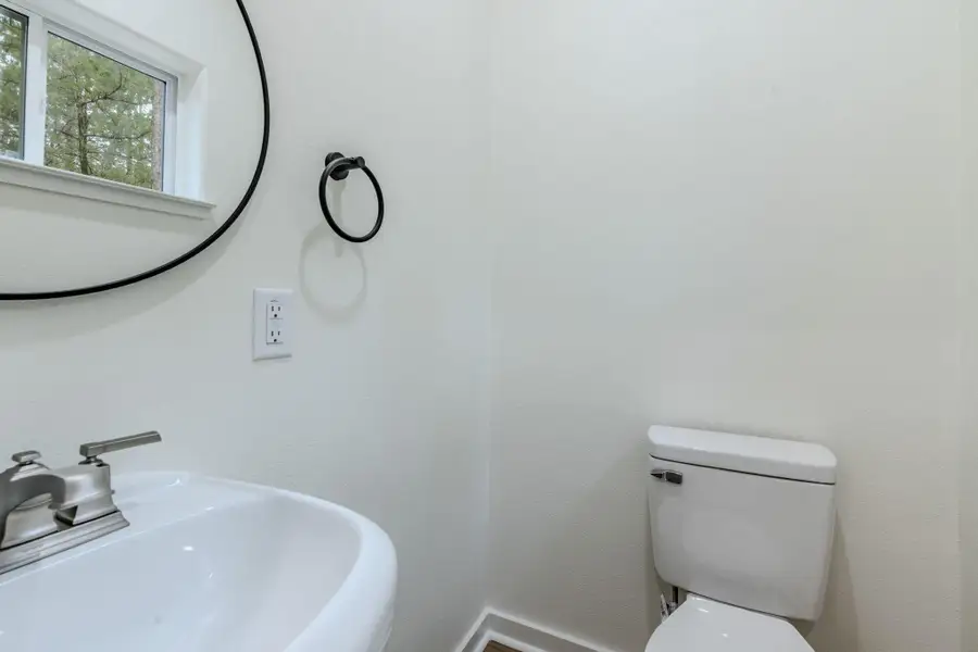 A well-appointed powder room features a sleek vanity and commode, with natural light filtering through the window. A well-appointed powder room features a sleek vanity and commode, with natural light filtering through the window.