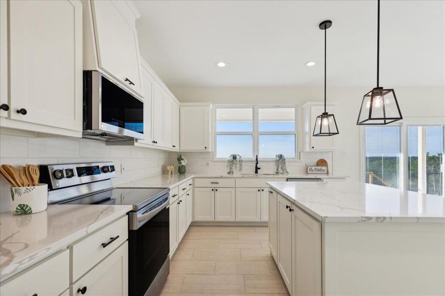 Kitchen featuring white cabinetry, backsplash, stainless steel appliances, and light stone countertops