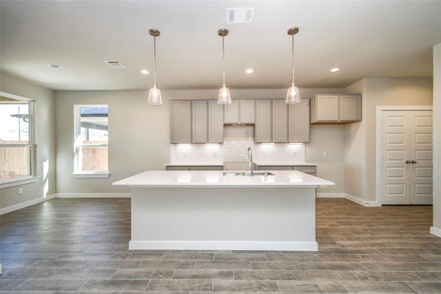The kitchen is a culinary haven, featuring granite countertops, a tile backsplash, stainlesssteel appliances, 42” upper cabinets, and undercabinet lighting. Sample photo of completed home with similar floor plan. Actual colors and selections may vary.