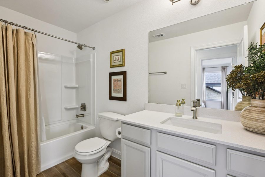 Bathroom featuring a bathtub with shower, a vanity with a white countertop and white cabinetry, and wood-style flooring