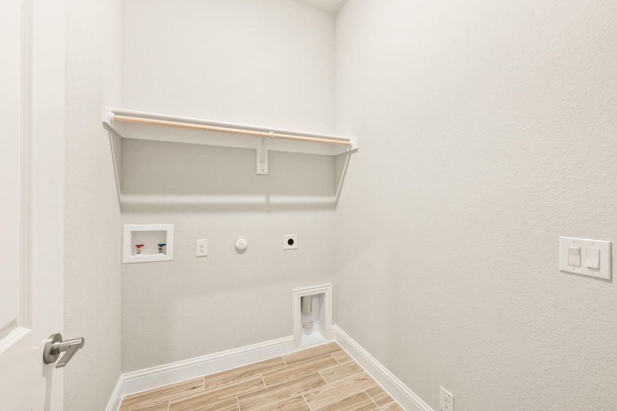 Laundry room with wall-mounted shelf, washer hookups, gas dryer connection, and wood-look tile floor Laundry room with wall-mounted shelf, washer hookups, gas dryer connection, and wood-look tile floor