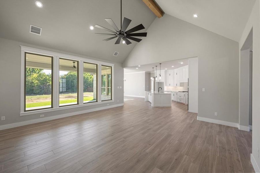 Living room featuring a vaulted ceiling with a beam, big windows letting in natural light, vaulted ceiling with beam, ceiling fan, and open floorplan